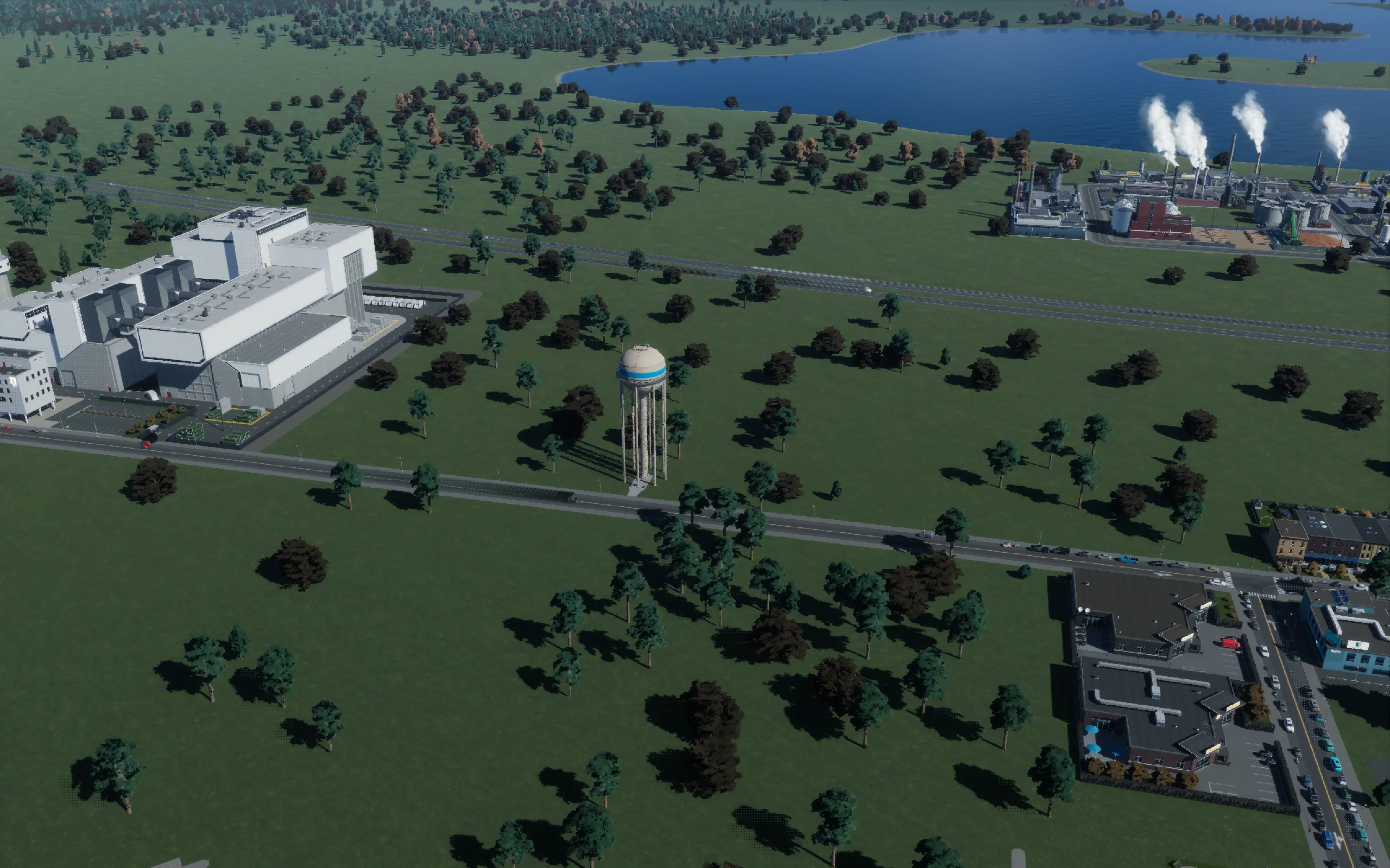 18:11 — Native 2560×1600 Photo Mode photograph: incinerator at left, the first new water tower beside the road, and the old coal plant beyond the highway. The prison and the other two towers had not yet been added.